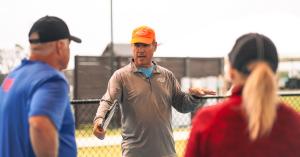Coach Tony Roig speaking with adult players at an outdoor pickleball camp