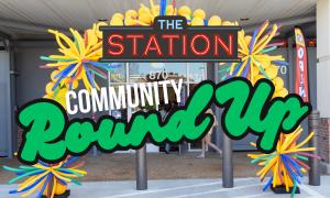 Promotional graphic for The Station's Community Round Up event featuring the storefront entrance decorated with a colorful yellow balloon arch and multicolored balloon bursts. Large text overlay reads "The Station Community Round Up," with the store entra
