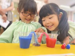 Two young children mixing blue and red colored water in clear cups