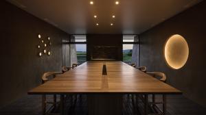 Long wooden dining table in Ne's earthen-walled dining room at dusk