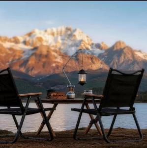 Two SunnyFeel folding chairs and a table beside a lake facing snow-capped mountains at sunrise