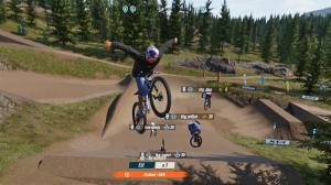 Third-person view of a mountain biker performing a mid-air trick on a dirt track, with other bikers doing their own tricks in the background.