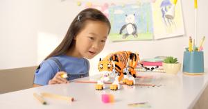 Young girl sitting at desk in her room looking at a LEGO tiger that has come to life.