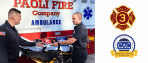 Two Paoli Fire Company paramedics exchanging medical supplies in front of an ambulance, with fire and autism center logos beside them.