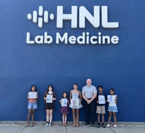 Winners of HNL Lab Medicine's 2026 Kids Art Contest pose with their artwork outside HNL Lab Medicine alongside President and CEO Martin K. Till.