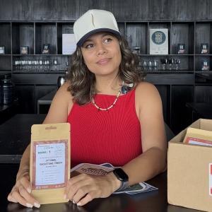 Kathya Irias holds the Cup of Excellence Rank 1 Parainema sample bag at Spirit Origin's Coffee Omakase in Roatán, Honduras
