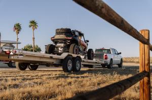 UTV Source Segway Villain being backed off an all-aluminum Aluma wide-body tandem trailer behind a white Ram pickup on open desert terrain at Ocotillo, California.