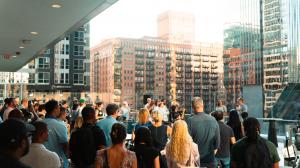 Lofty Angels Summit attendees gather on a sunlit rooftop deck surrounded by downtown Chicago buildings.