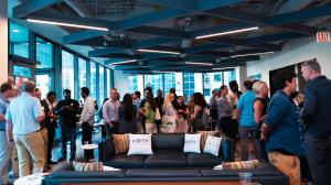 Lofty Angels Summit attendees networking in a modern indoor lounge overlooking downtown Chicago.