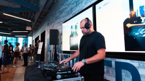 Recordng artist and electronic musician Com Truise performs a private DJ set at the Lofty Angels Summit as attendees mingle inside the rooftop event space.