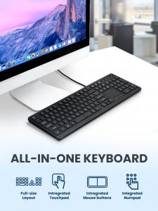 PERIBOARD-513 III black wired keyboard connected to a desktop monitor, showing its full-size layout, integrated touchpad, mouse buttons, and numeric keypad.