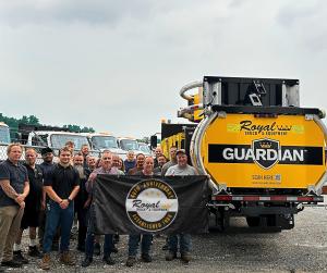 Group of Royal Truck & Equipment employees standing beside a Guardian truck mounted attenuator (TMA) truck at the company's Pennsylvania facility. Team members hold a black banner displaying Royal Truck & Equipment's 40th Anniversary logo, while additiona