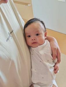 Baby Zi Han rests against his parent’s chest while being held securely in their arms.