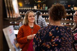 Image features Cameron Stearns, CEO/CFO of Mountain Rose Herbs smiling while talking with a person inside the Mountain Rose Herbs Mercantile.