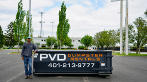 Jamaal Hazard, owner of PVD Dumpster Rentals, standing beside a branded roll-off dumpster in Cranston RI