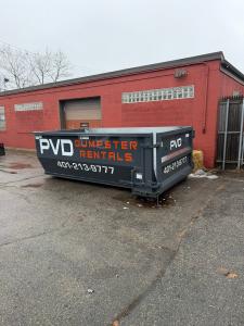 PVD Dumpster Rentals commercial roll-off dumpster in the back parking lot of a store in Cranston RI