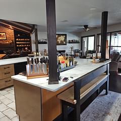 Dark cabinetry, wood accents, hex backsplash, island with stools in a beautiful renovated kitchen