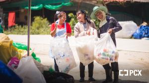 Three women recovery workers hold bags of collected plastic bottles at a PCX - supported plastic recovery project in Thailand.
