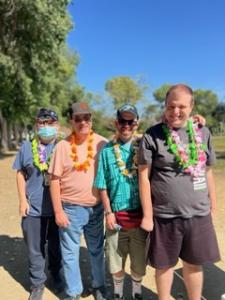 Four men who participate in Hope Services programs stand together outdoors near the bocce ball courts, smiling and enjoying inclusive recreation for people with intellectual and developmental disabilities.