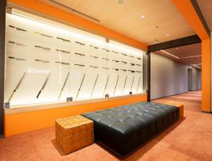 Entrance area of TAIMATSU main office with orange accents, knife wall display, and seating area.