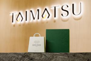 Shopify milestone award displayed in front of the TAIMATSU logo, celebrating MUSASHI JAPAN reaching 100,000 orders.