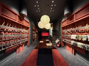 Interior of MUSASHI JAPAN Kyoto Kawaramachi Station Front Store with knife displays, red shelving, and a central table.