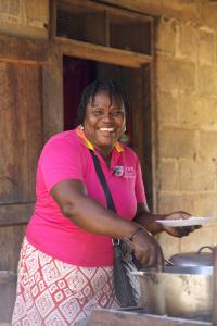 Image of Haitian woman serving food at her home based restaurant