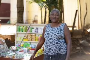 Haitian woman standing in front of portable display showing goods she has for sale