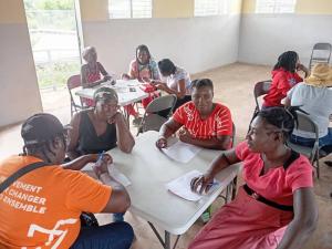 Haitian women seated at a small table discussing their business plans