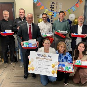 GBU Life employees and producers standing in a group holding kits that were prepared during a Birthday Bash event at the GBU Life Home Office
