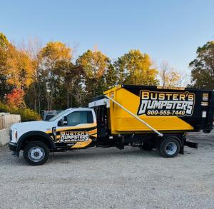 Buster's Dumpsters delivery truck carrying a roll-off dumpster for dumpster rental in Lansing MI