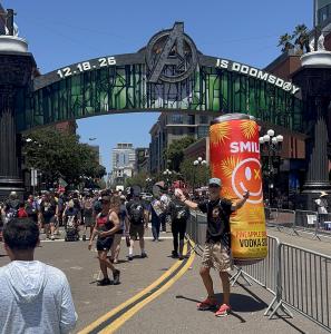 Smile Spirits founder Mitchell Bailey wearing a giant inflatable “Stan the Can” backpack beneath the Avengers arch at San Diego Comic-Con in downtown San Diego