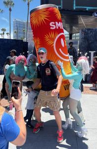 Comic-Con attendees in alien costumes pose with Smile Spirits founder Mitchell Bailey and the giant inflatable “Stan the Can” backpack in downtown San Diego during Comic-Con