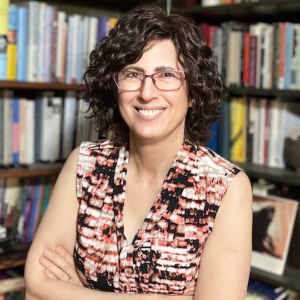 Colorful headshot of Danielle Ofri, with arms crossed in front of bookshelves
