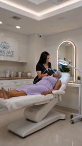 A clinician performs an advanced aesthetic facial treatment on a patient in a modern treatment room at Park Ave Cosmetic Center, featured in the original episodic series Park Avenue.