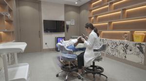 Hair restoration specialist performing a scalp assessment during a pre-treatment consultation in a modern clinical examination room.