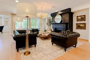 Living room with black leather Chesterfield couches and custom black fireplace, brass and glass chandelier, RH floor lamps and coffee table