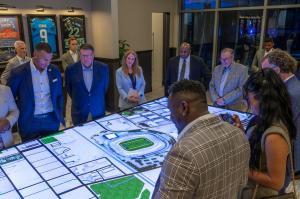 Visitors explore the interactive stadium model table at the Bank of America Stadium Experience Center opening.