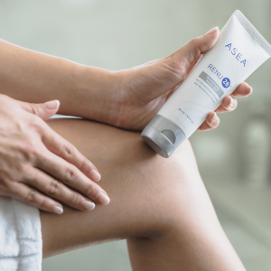 A woman applying RENU28 indoors after sun exposure.