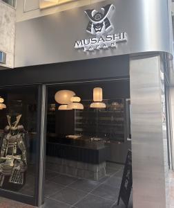 Exterior view of MUSASHI JAPAN Shibuya Center-Gai Store in Tokyo with store signage and Japanese kitchen knife displays visible inside