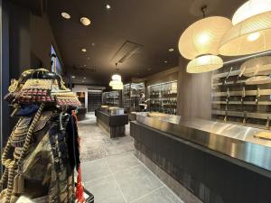Interior of MUSASHI JAPAN Shibuya Center-Gai Store with samurai armor, lantern lighting, and Japanese kitchen knife displays