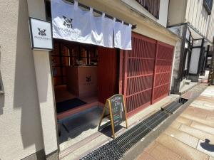Exterior view of MUSASHI JAPAN Kanazawa Higashi Chaya Store with white noren curtain and red lattice storefront