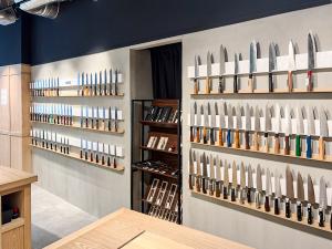 Wall display of Japanese kitchen knives inside MUSASHI JAPAN Shibuya Main Store with wooden counters and product shelves