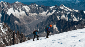 Two people walking through a snowy mountainous landscape