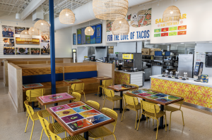 Interior image of the newest Tacodeli in Katy, TX. Showcasing the tables, decor, menu board, etc.