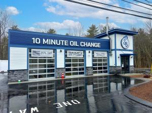 Exterior of a Strickland Brothers drive-thru oil change location, featuring a white-and-blue building with multiple drive-thru service bays, branded signage, and a parking area in front.
