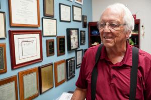 Doctor Samuel Prien looks at plaques on his office wall while reflecting on his career.