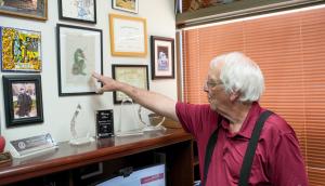 Doctor Samuel Prien points to artwork created by a former student hanging on his office wall.