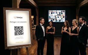 Wedding guests next to a Fotelya QR poster with a live photo wall displayed on a screen behind them