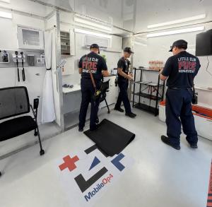 Three Little Elm firefighters inside an air-conditioned MobileOp4 mobile cooling station used for first responder rehab in Texas heat